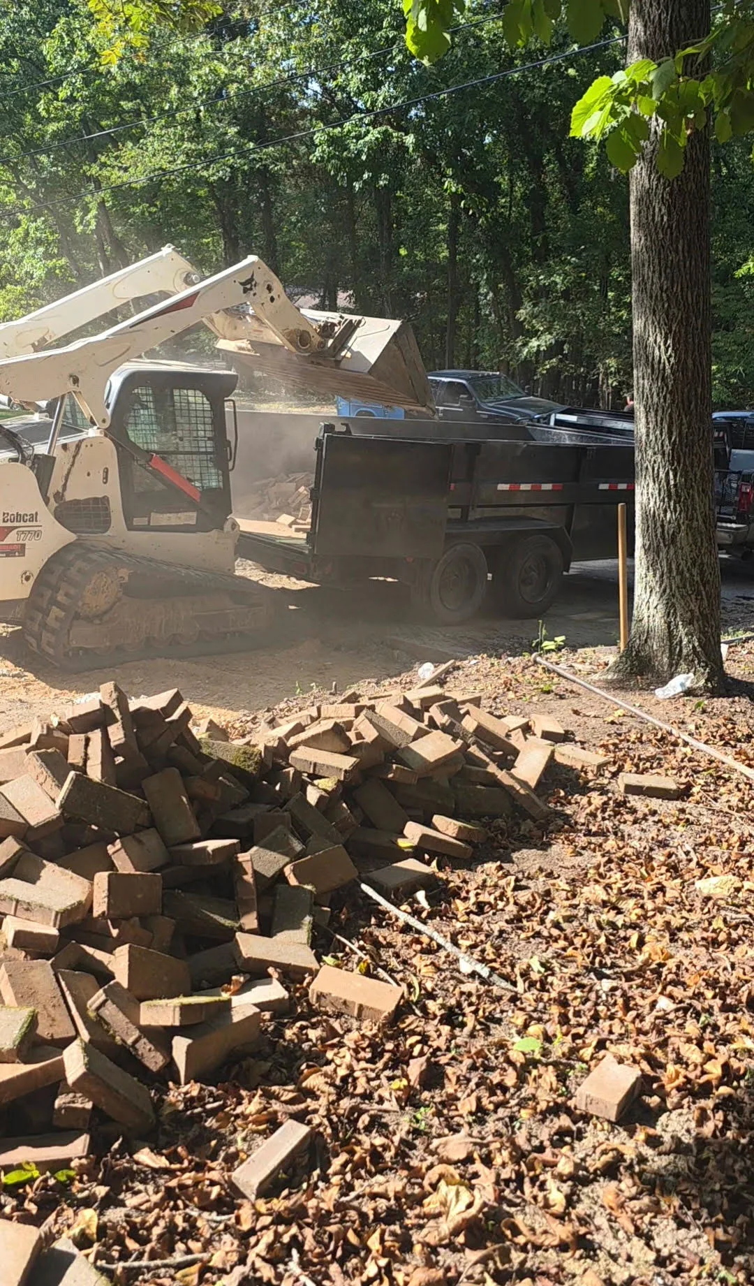 Skid steer loading masonry debris into a dump trailer.