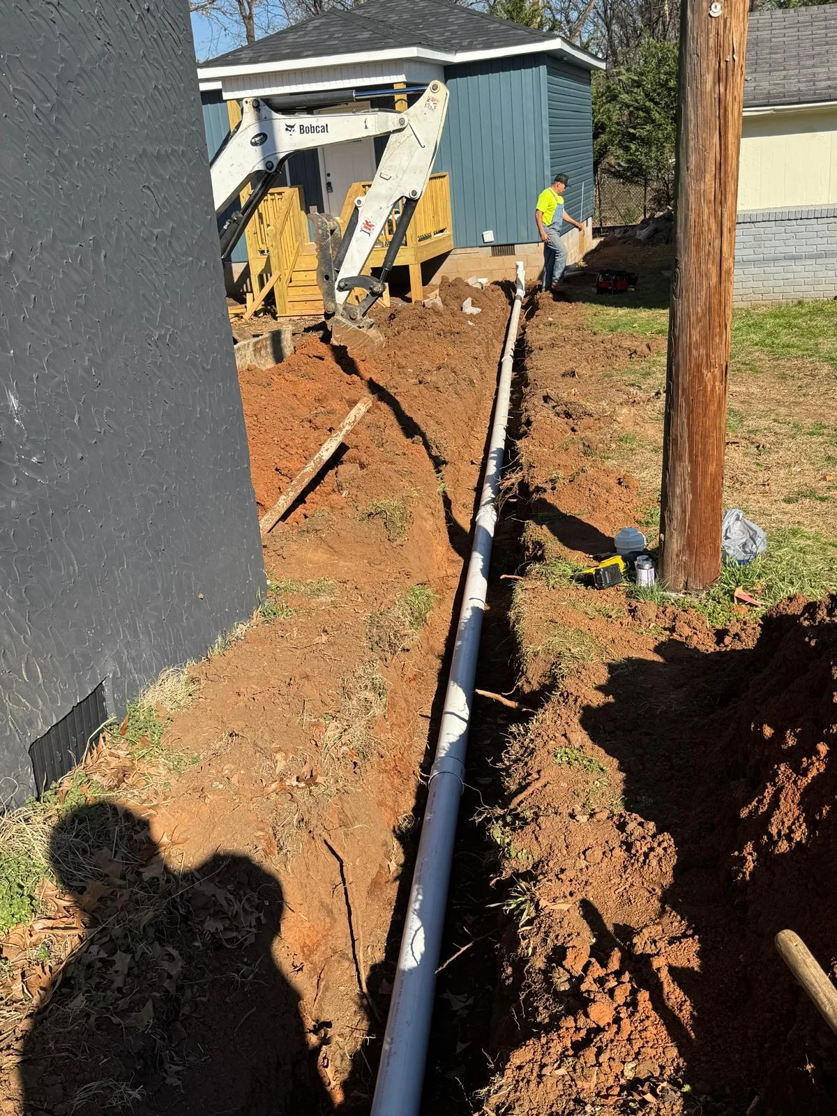 Pipe installed in a trench beside buildings.
