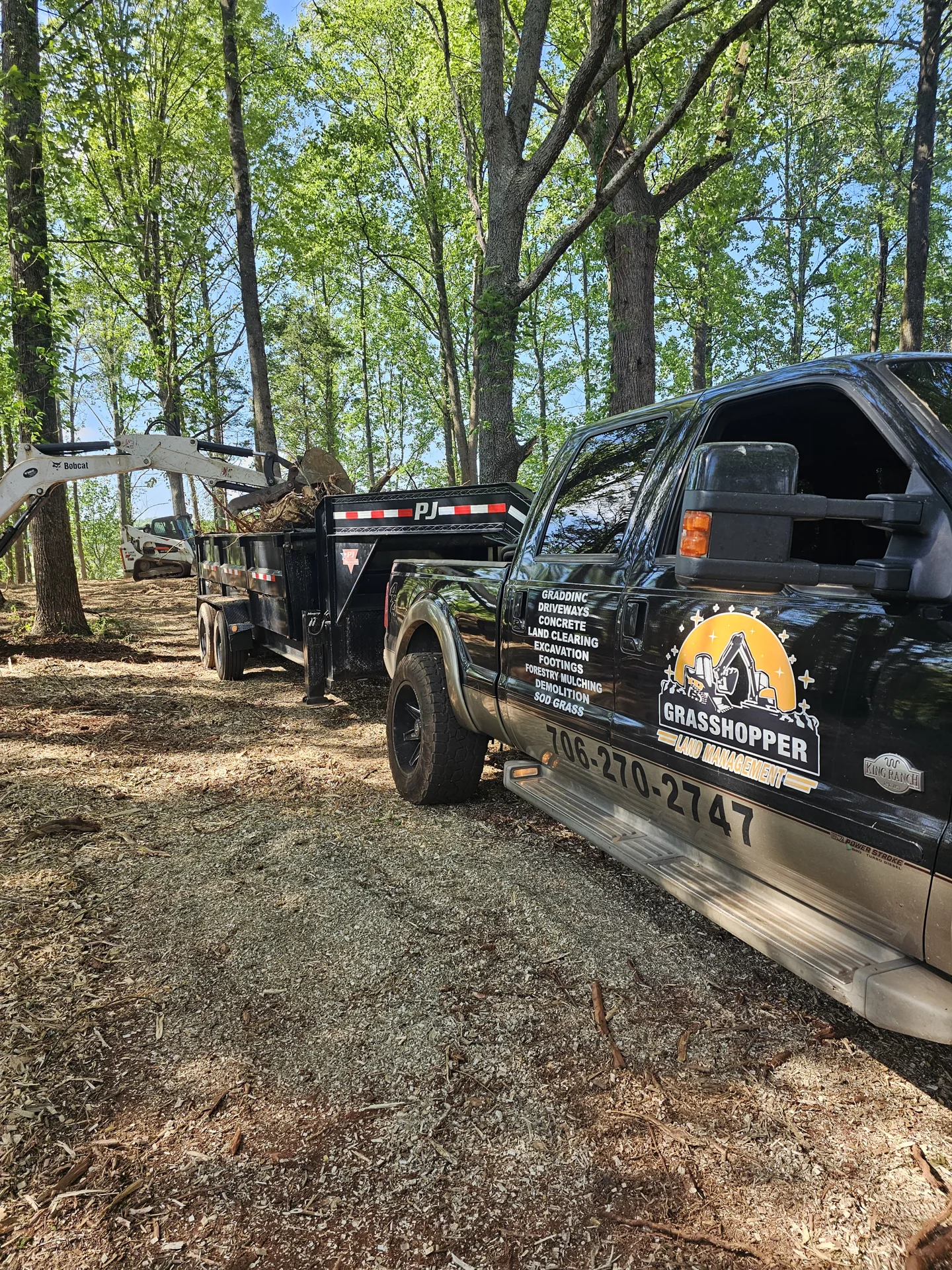 Branded truck and dump trailer carrying cut timber from a work site.